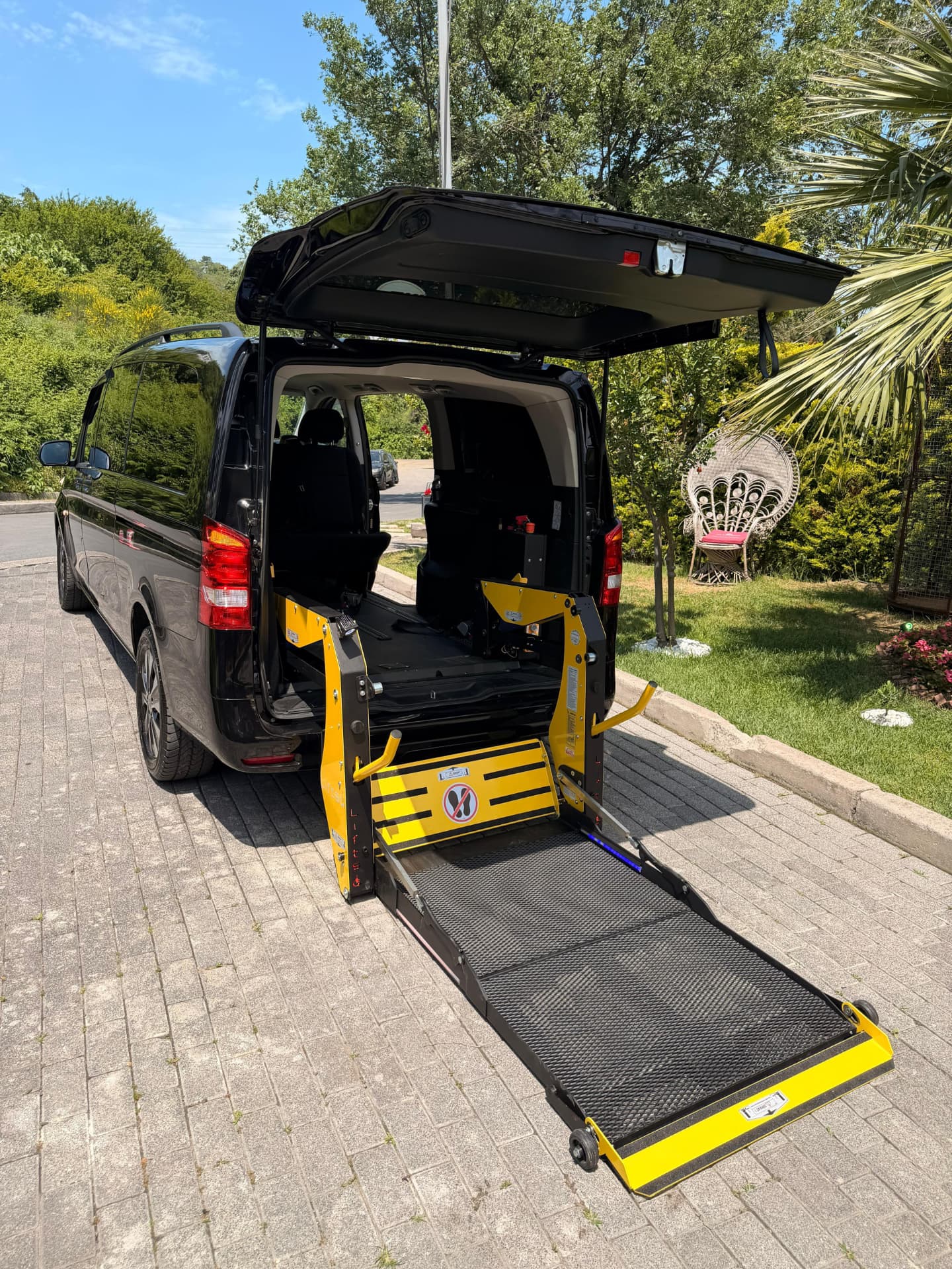 Wheelchair accessible Mercedes van with its rear electric wheelchair lift lowered to the ground
